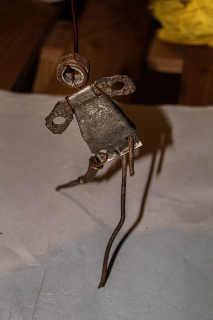 Metal fabrication of a woman like figure with different pieces of metal tied with copper